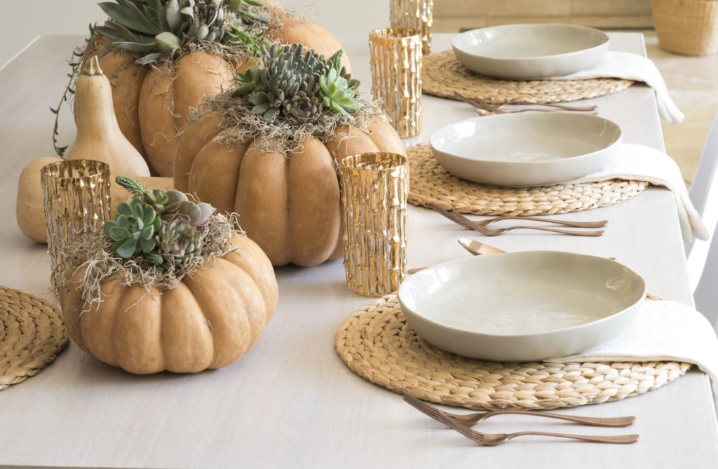 fall dining table decor with greenery inside pumpkins and wicker place settings