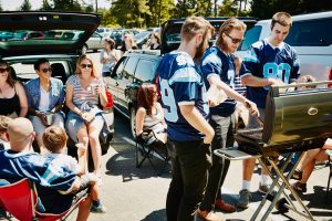 group of people in parking lot tailgating for football game