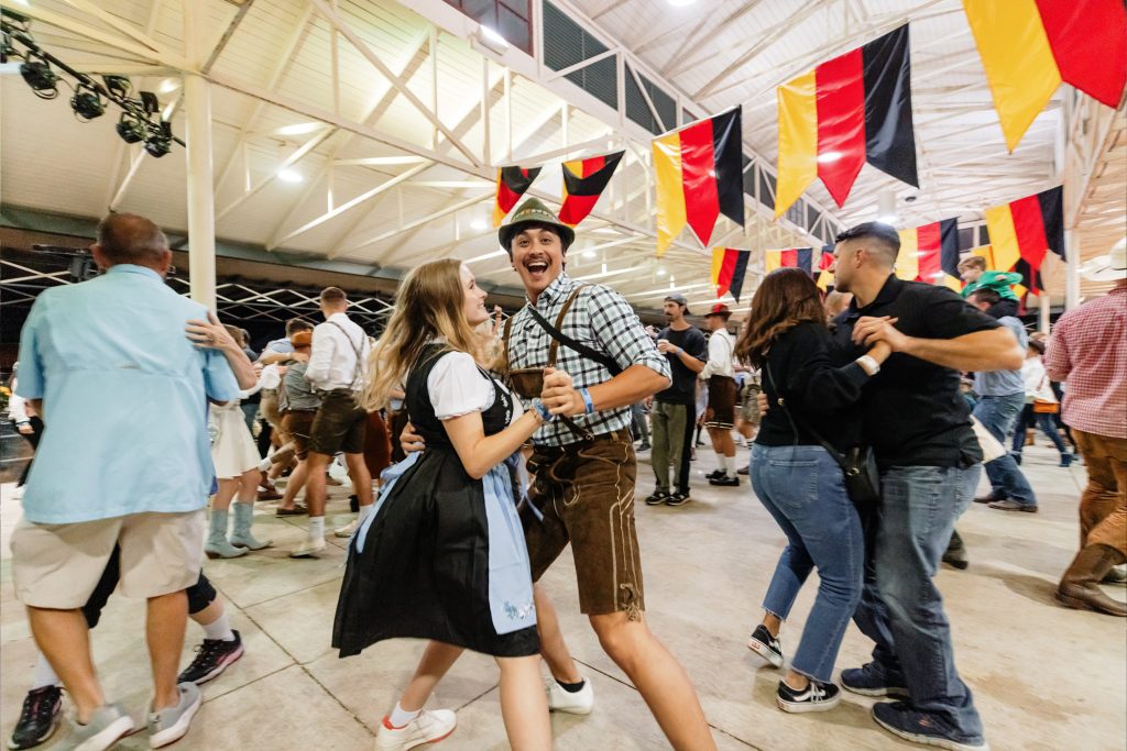 man and woman in dancing in traditional lederhosen