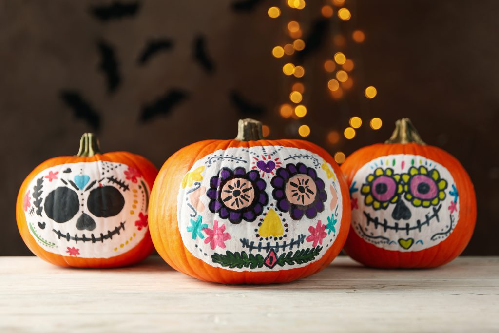 colorful sugar skulls painted onto three pumpkins