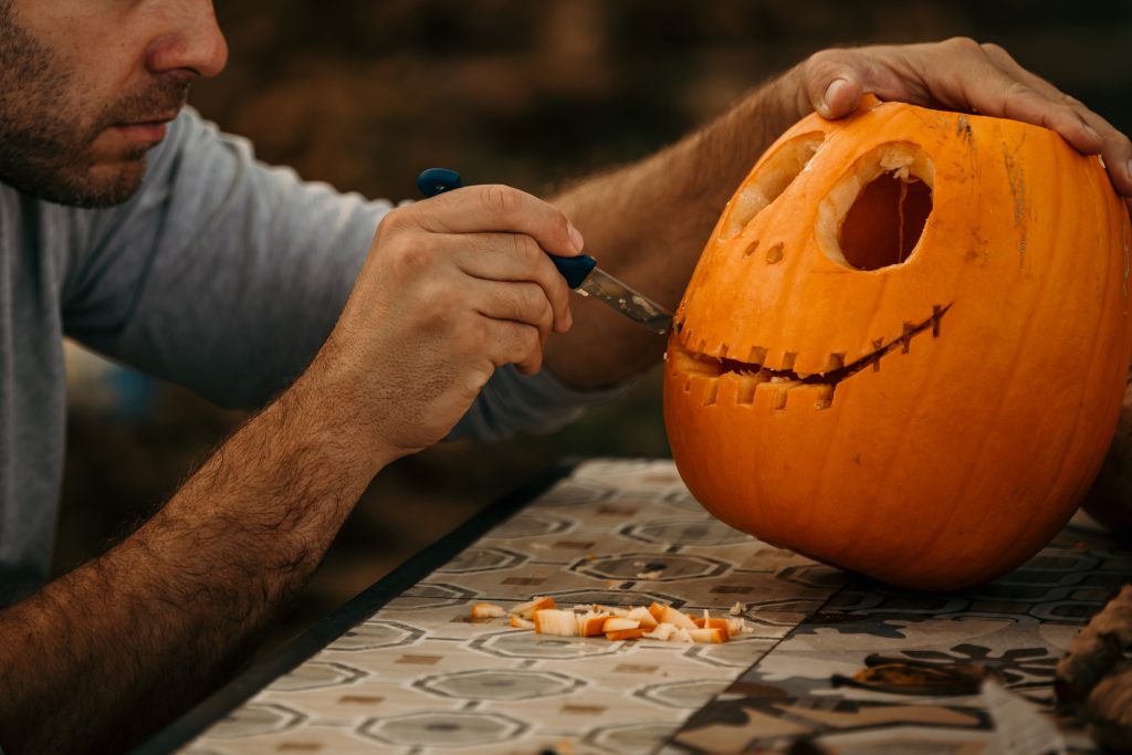 close up of man carving pumpkin for halloween