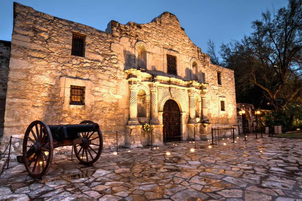 The Alamo lit up with warm, yellow lights in the evening