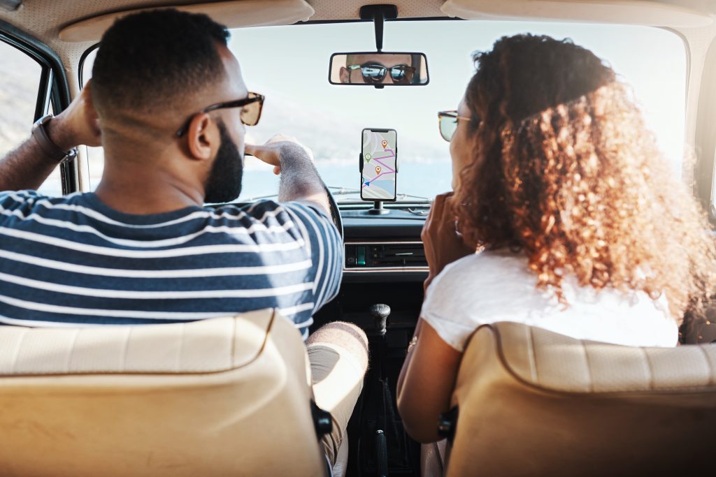 couple driving in car looking at road map directions on their phone