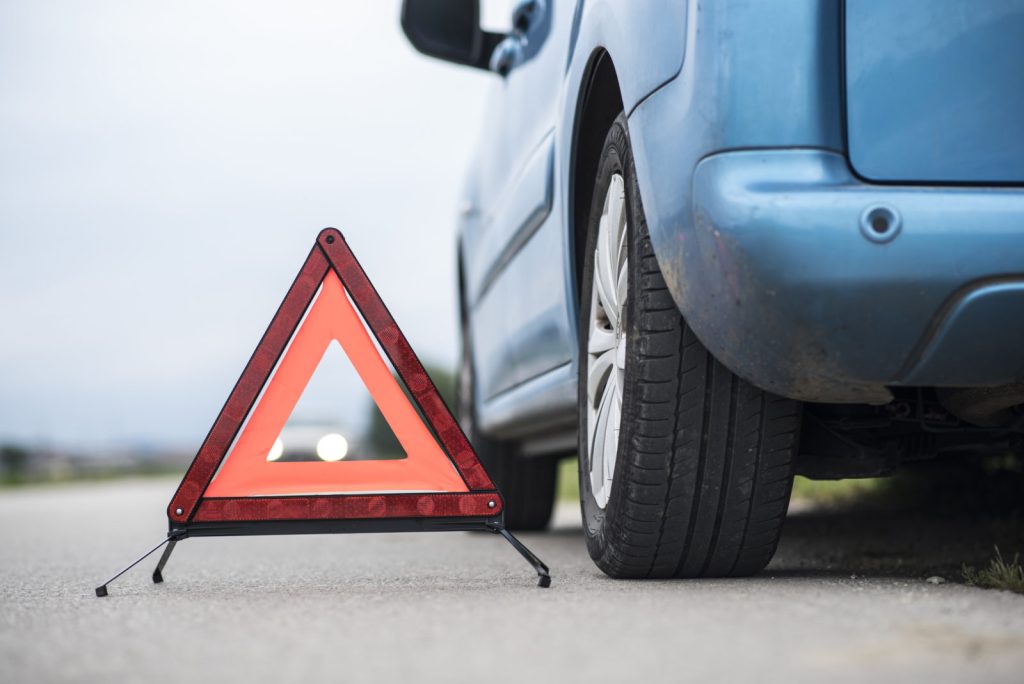 detail shot of a caution sign next to a car on the side of the road