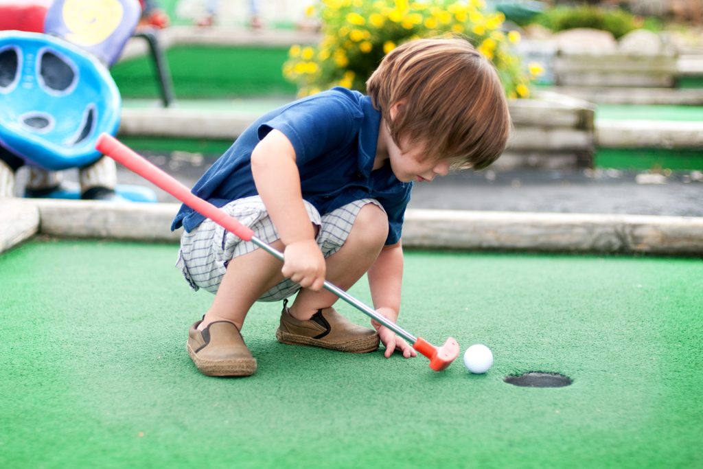 Little kid playing mini golf.