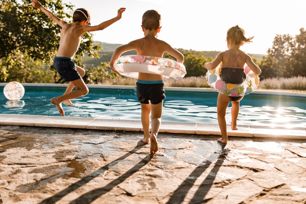 Kids with floaties jumping into a pool.