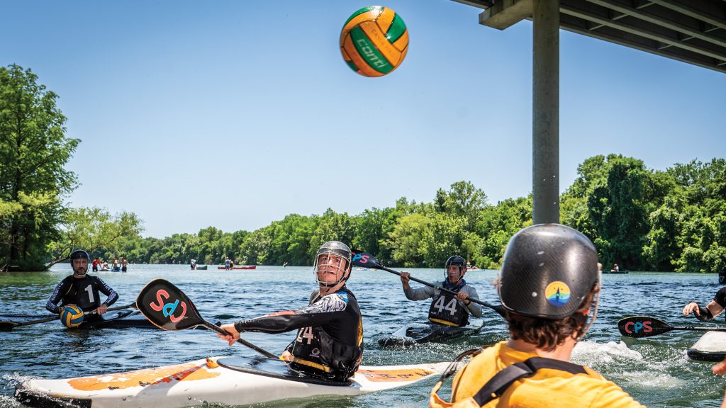 People playing kayak polo on a lake.