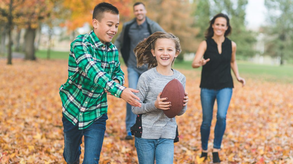 Family playing with a football outside.