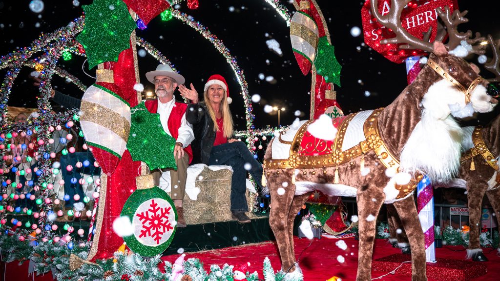 Man and woman on a holiday parade float.