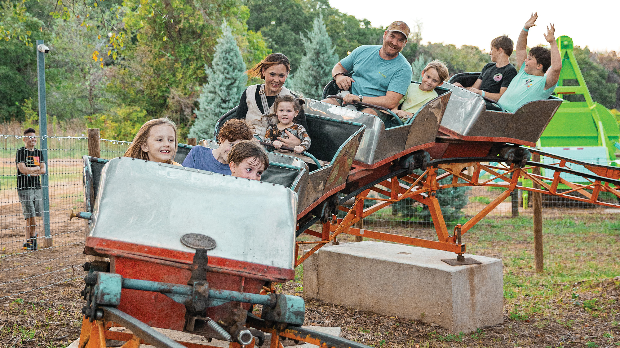 Kids and parents riding a small roller coaster.