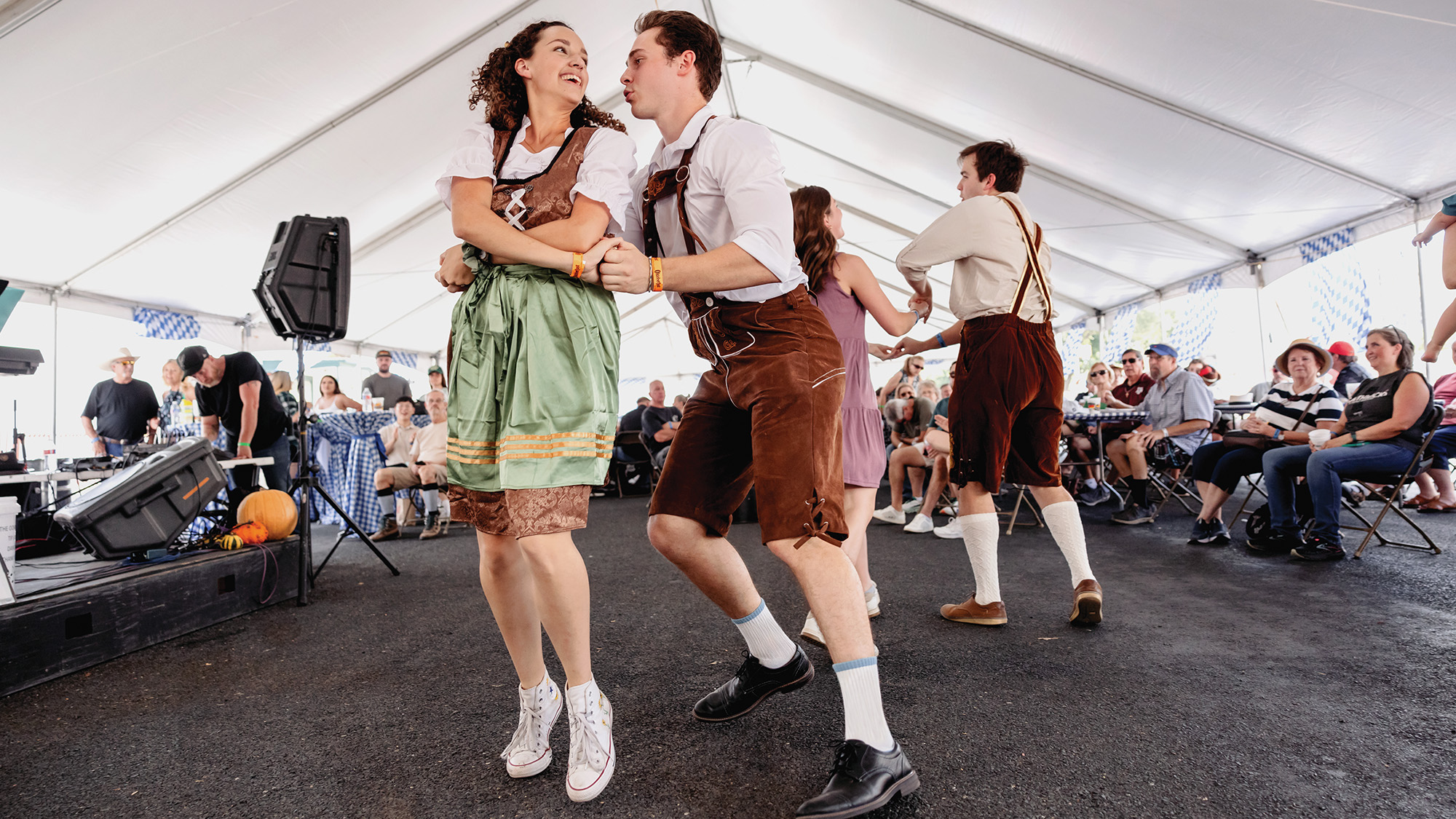 A man and a woman dressed in authentic German attire dancing at an Oktoberfest celebration.