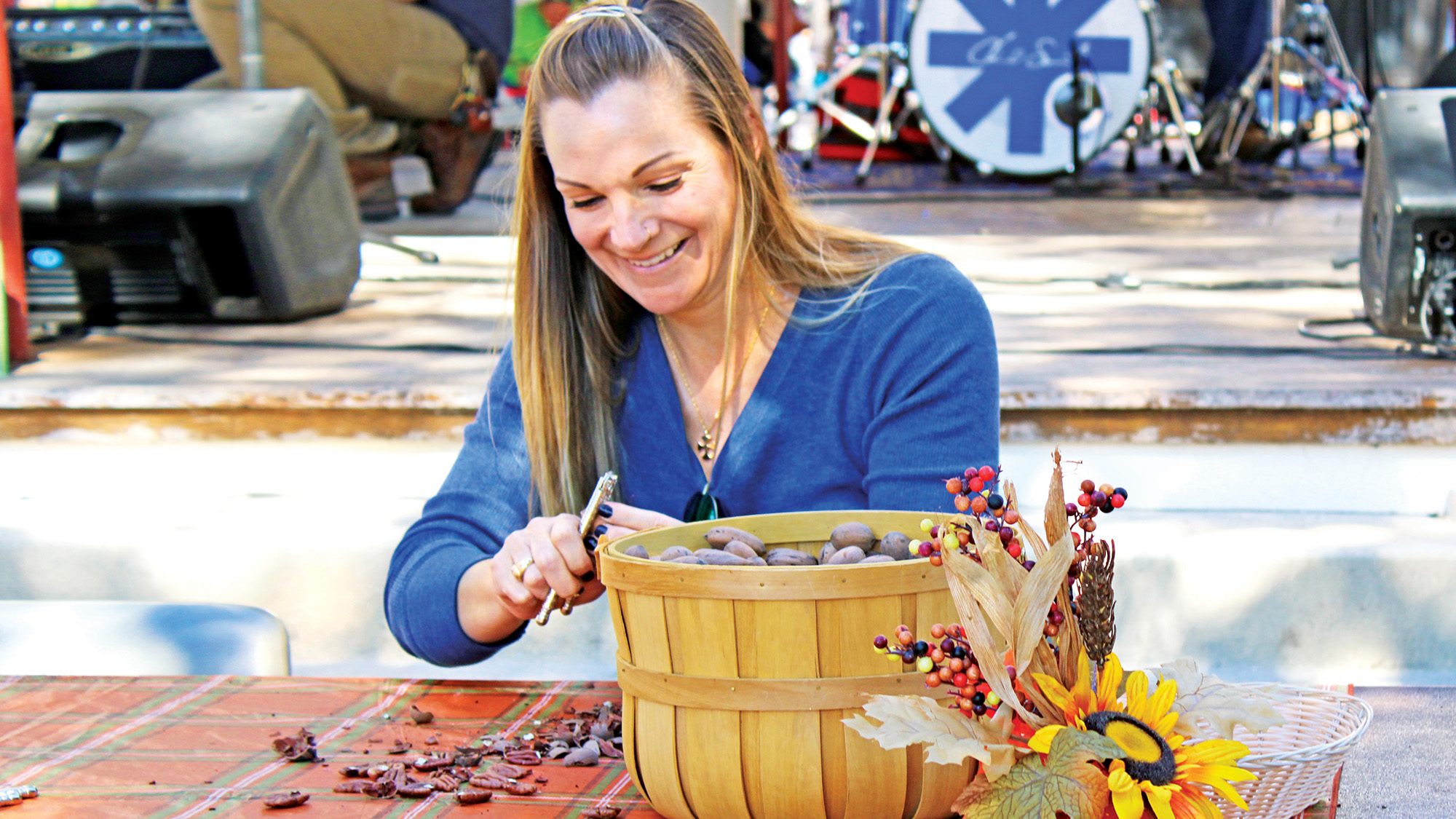 A woman cracking pecans at a festival.