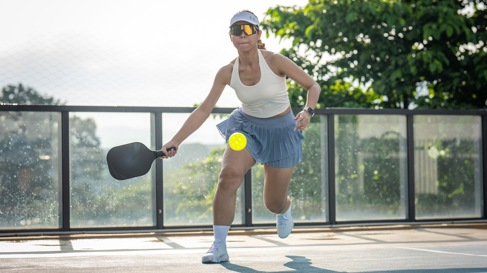 Woman playing pickleball outside.