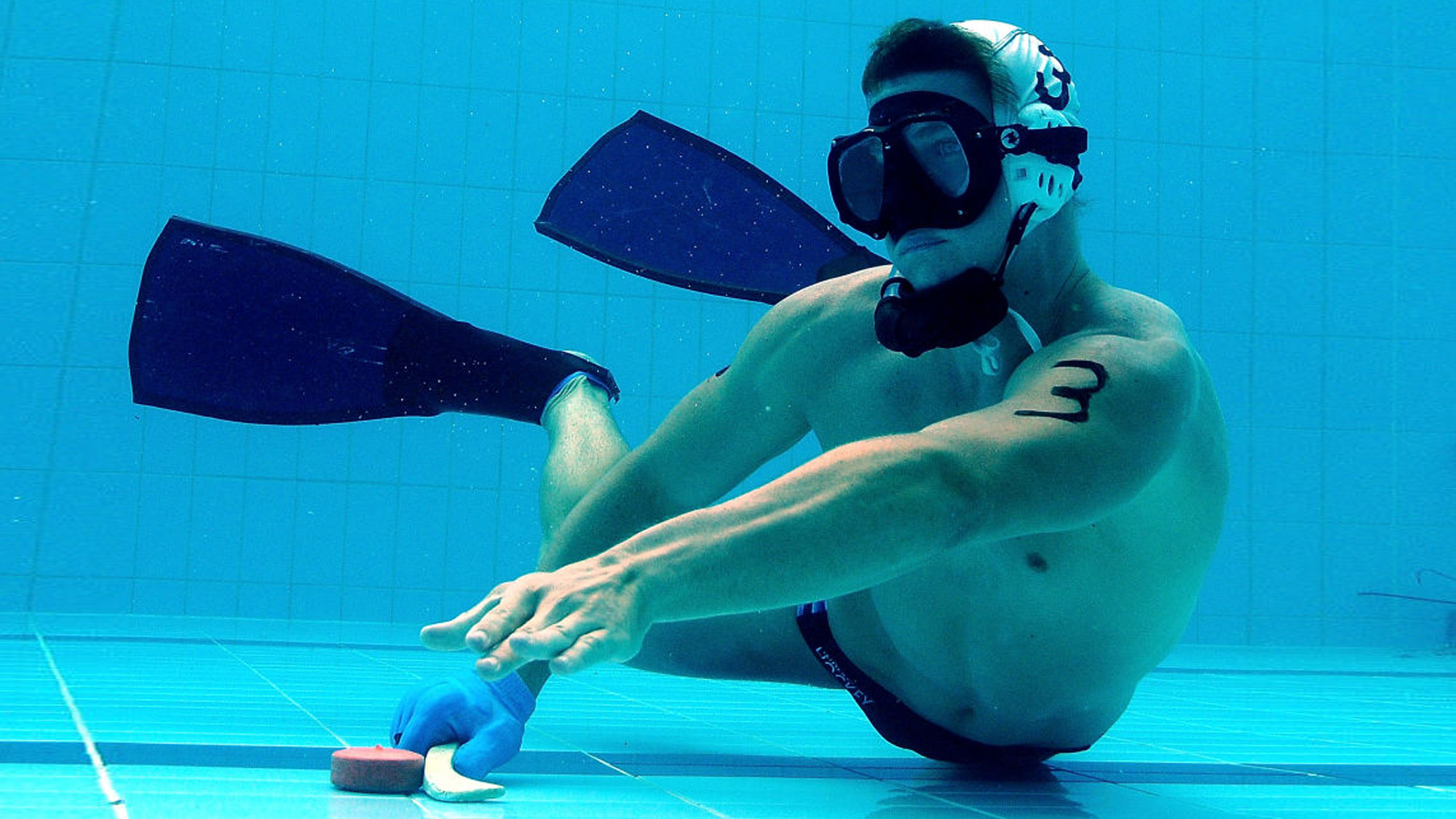 Man playing underwater hockey in a pool.