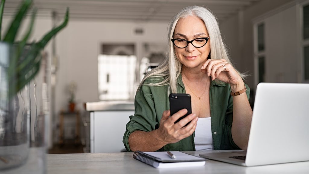 Woman at desk reading something on her phone.