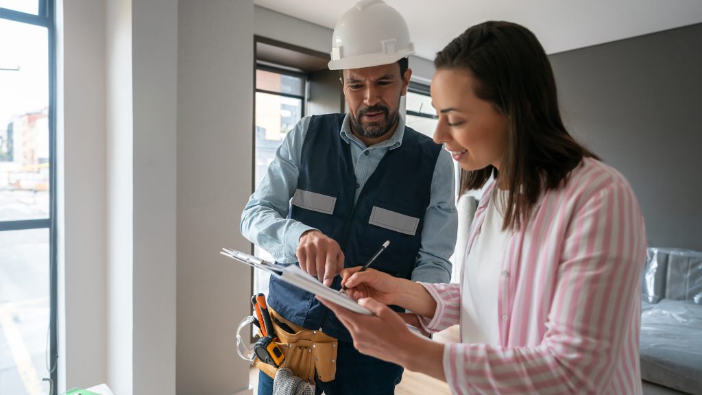 Woman signing paperwork with contractor.