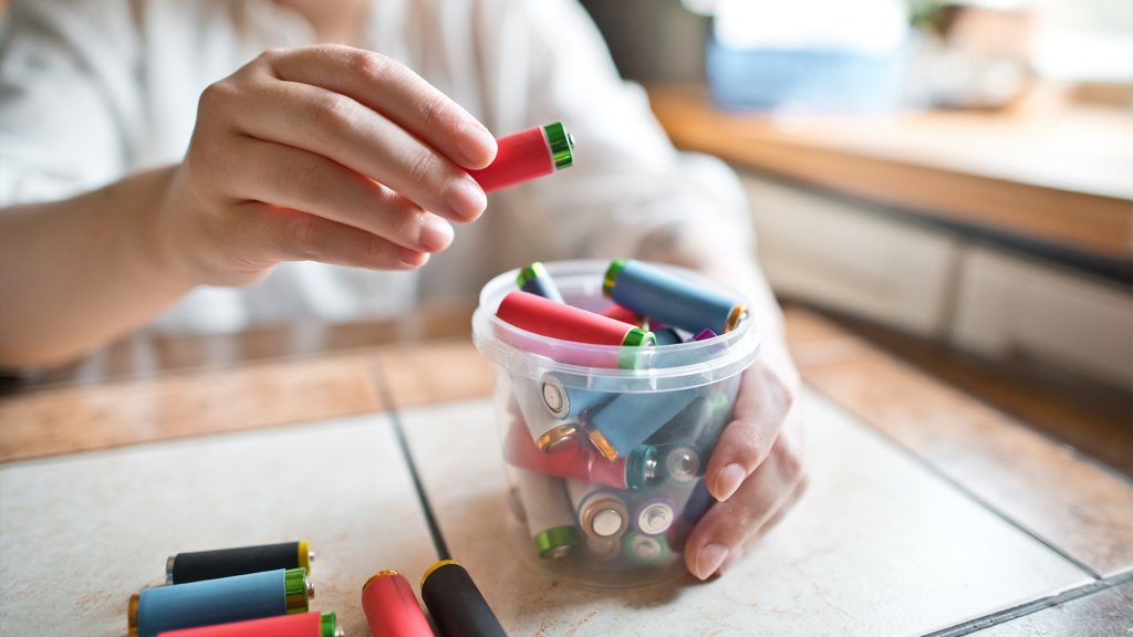 Person putting batteries in a container.