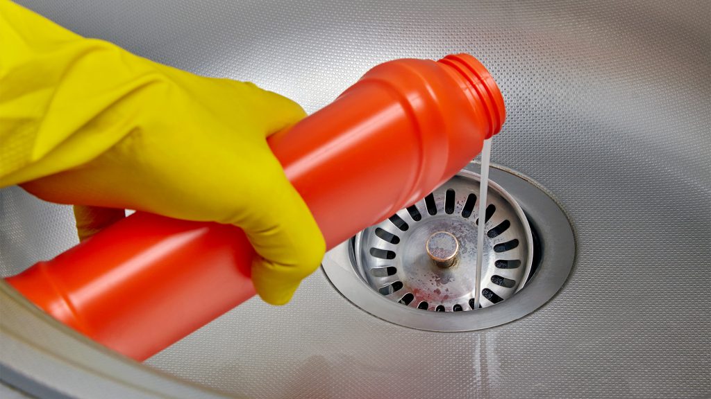 Person pouring chemicals in drain.
