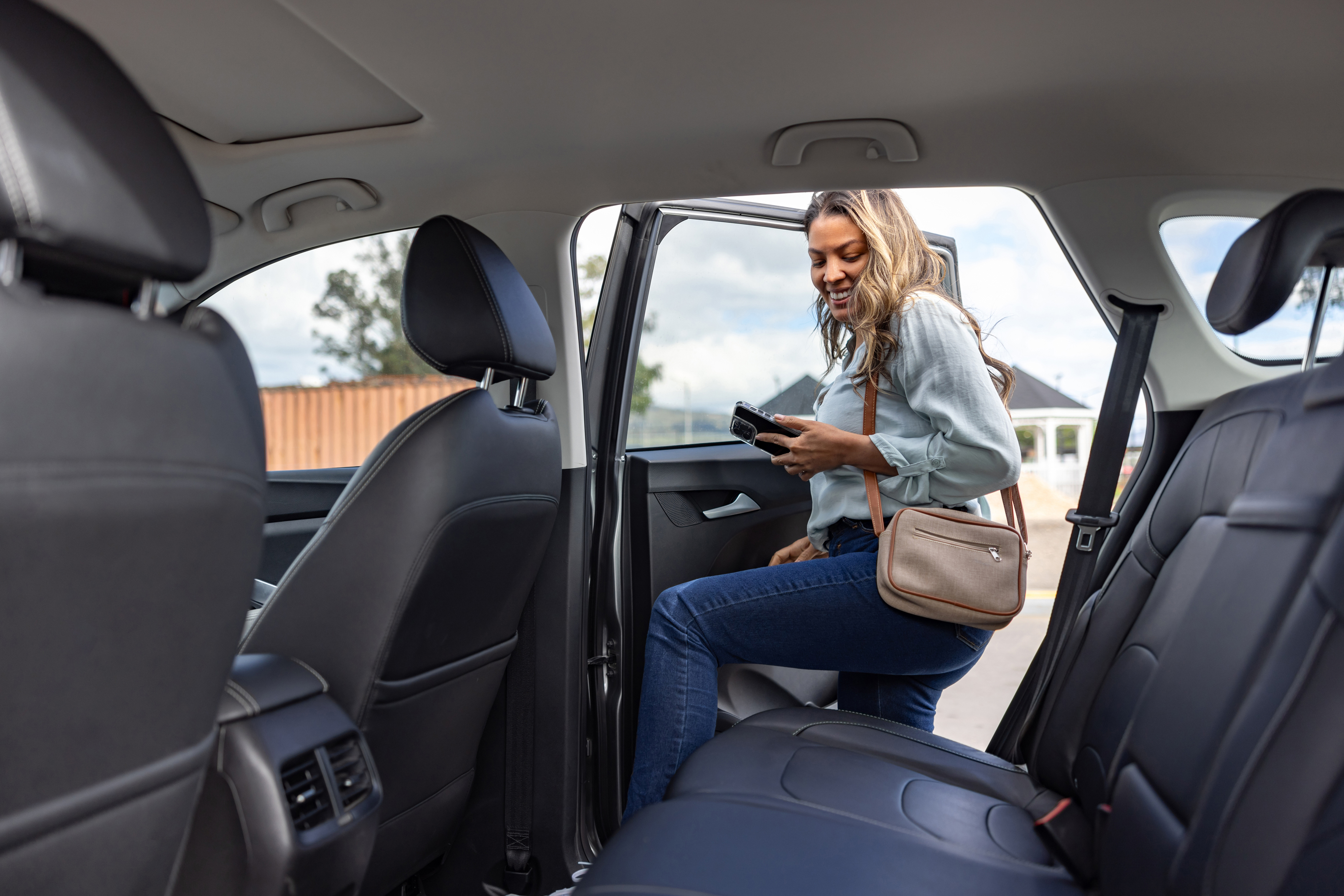 Woman getting into back seat of car.