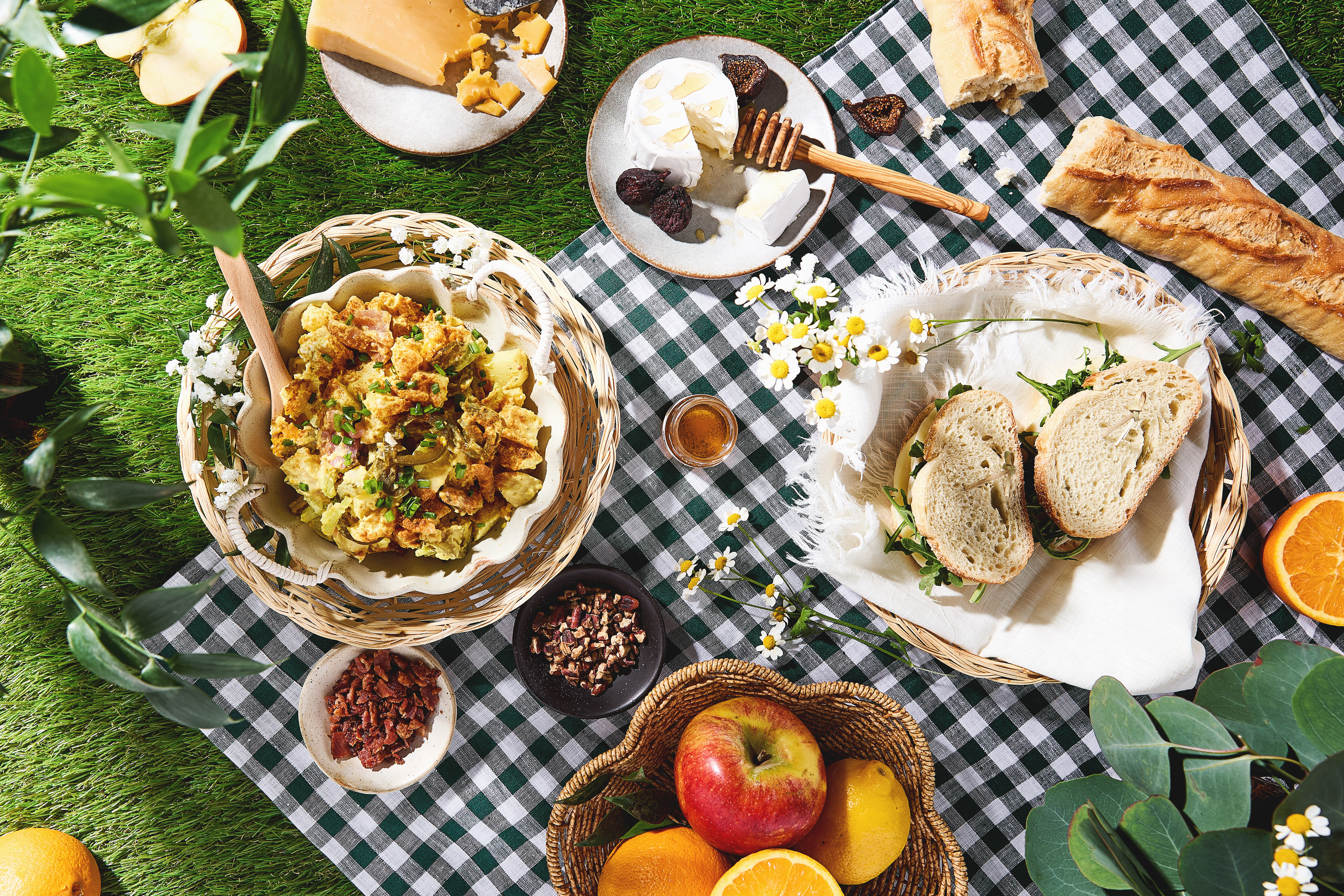 Overhead image of picnic with snacks and bowl of potato salad.