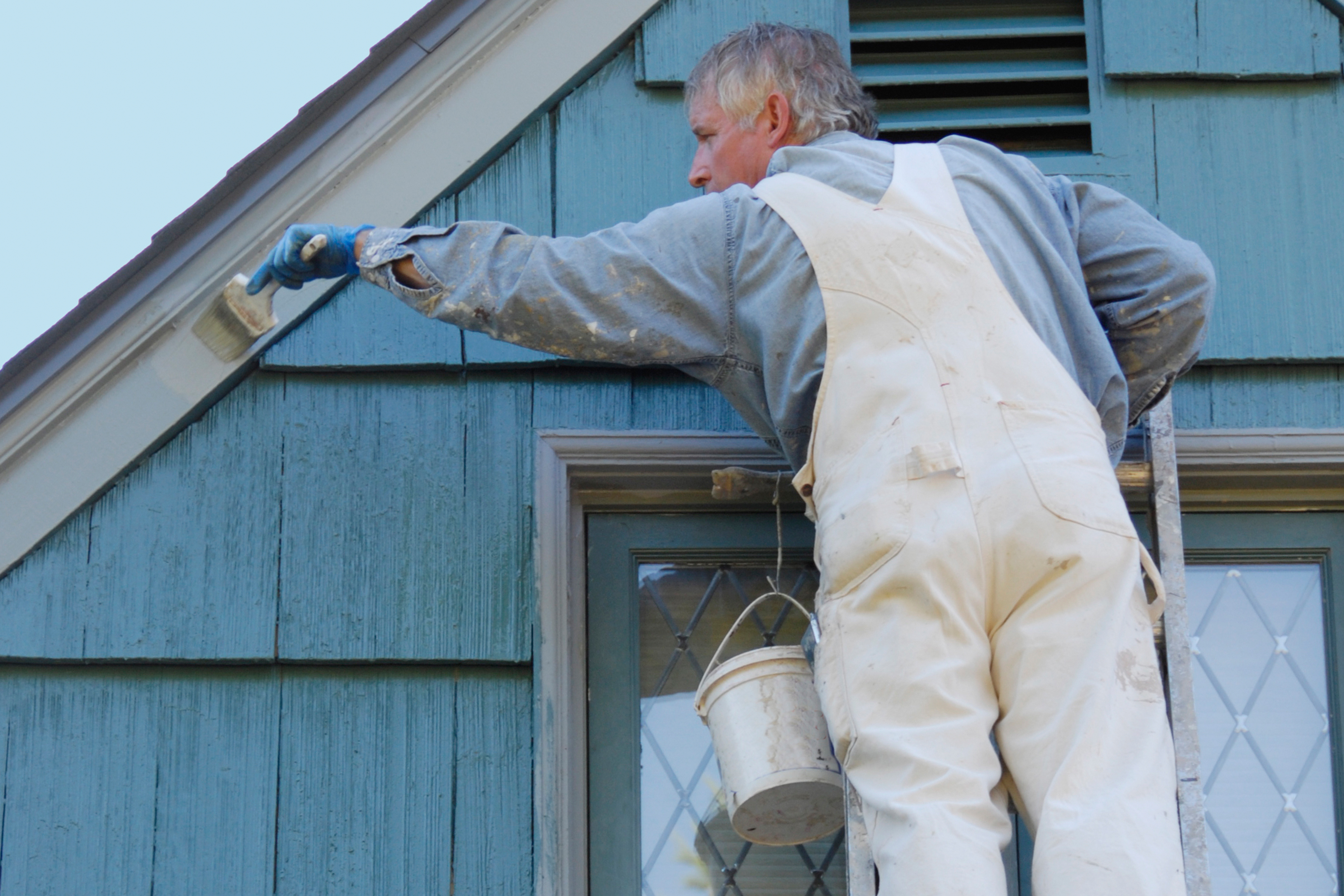 Man on ladder painting home.