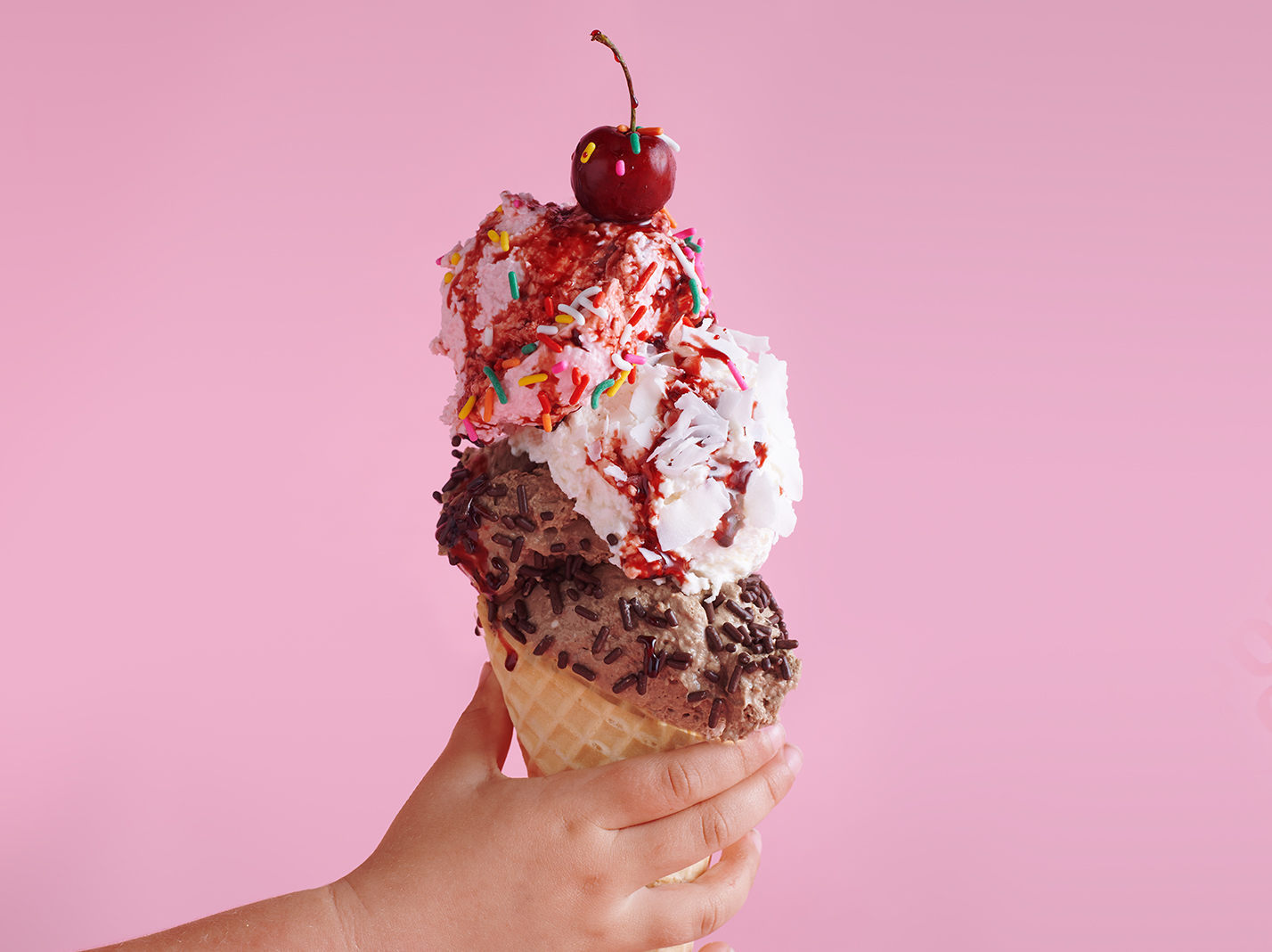 Ice cream in a cone with a cherry on top.