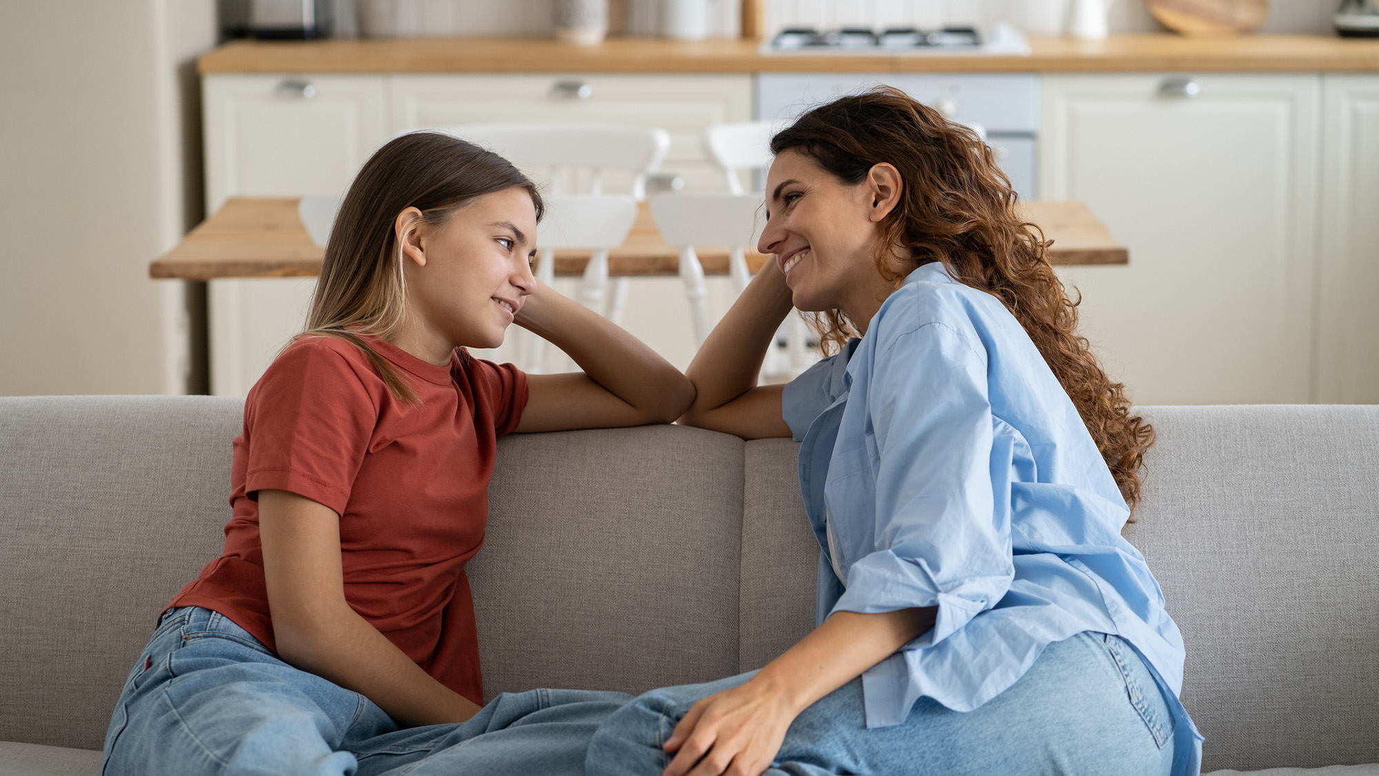Woman and young girl talking on couch.