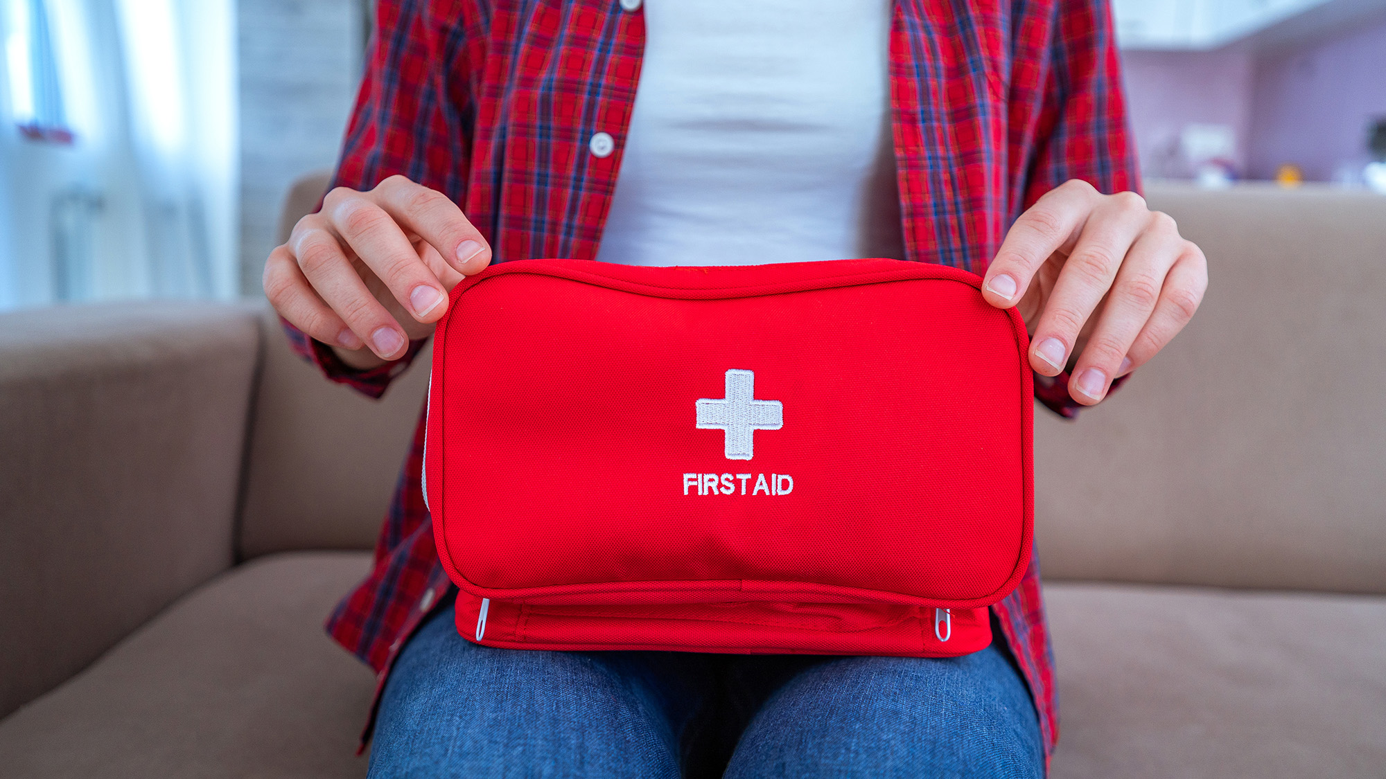 Person holding red first aid kit.