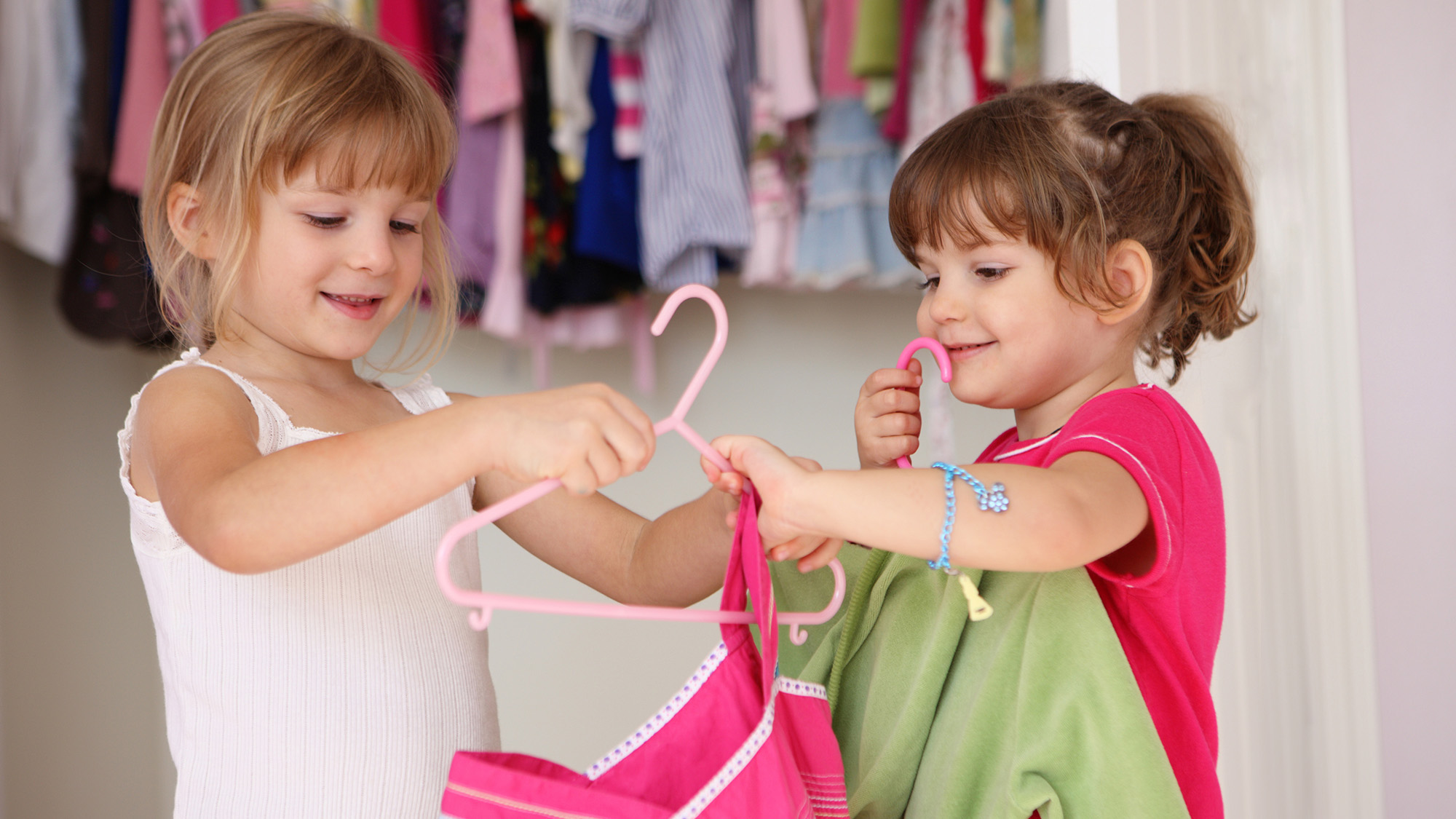 Two girls hanging up clothes on a hanger.