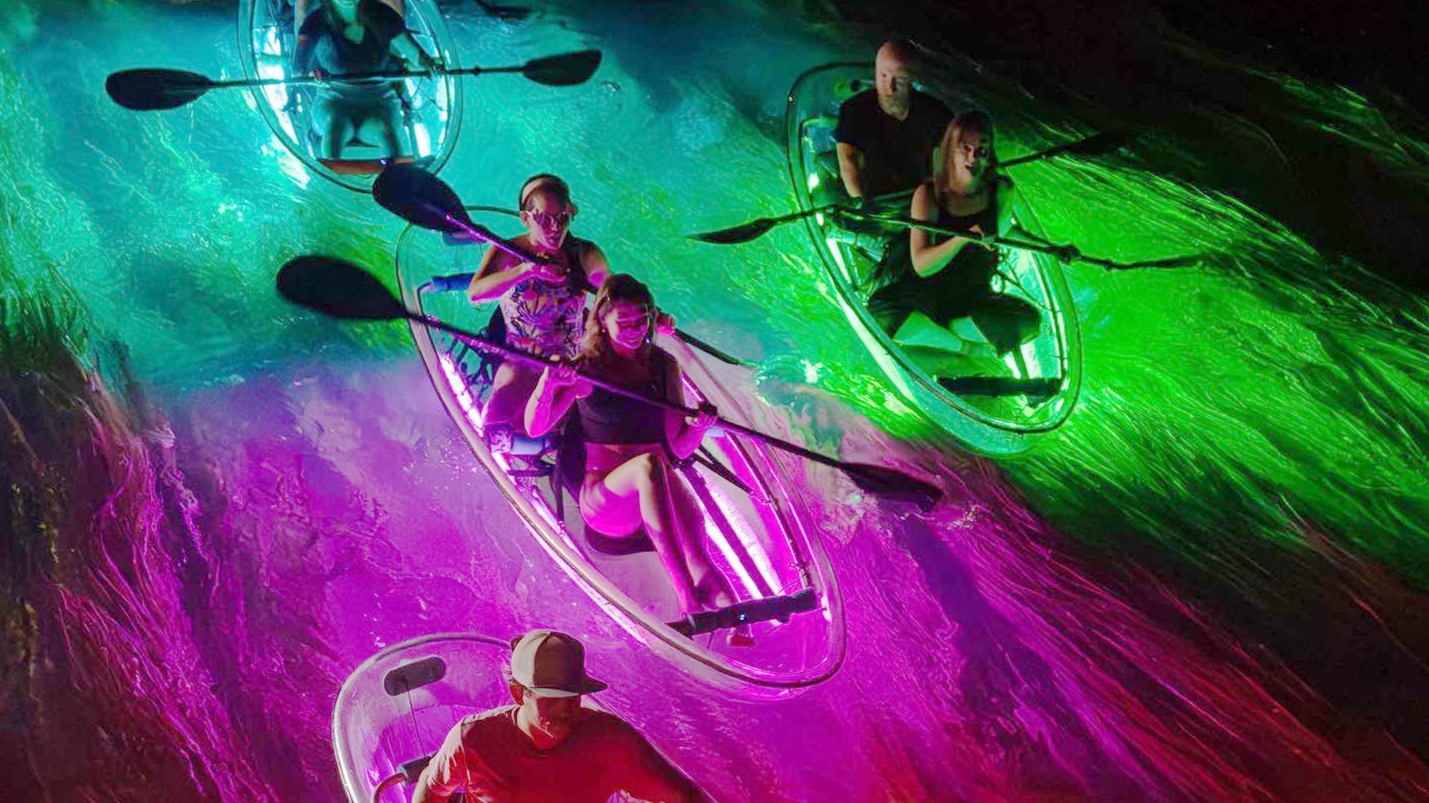 Group of people kayaking at night.