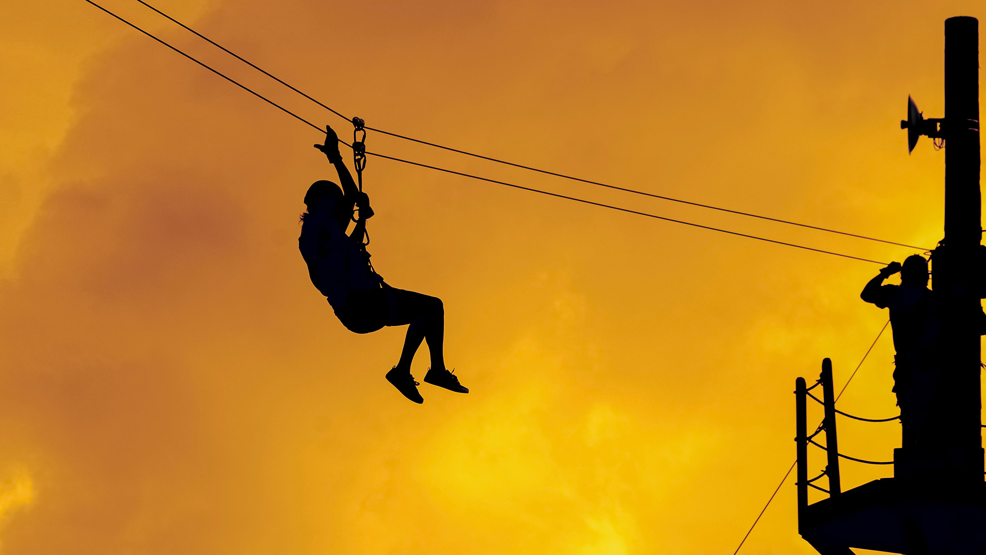 Person zip lining at sunset.