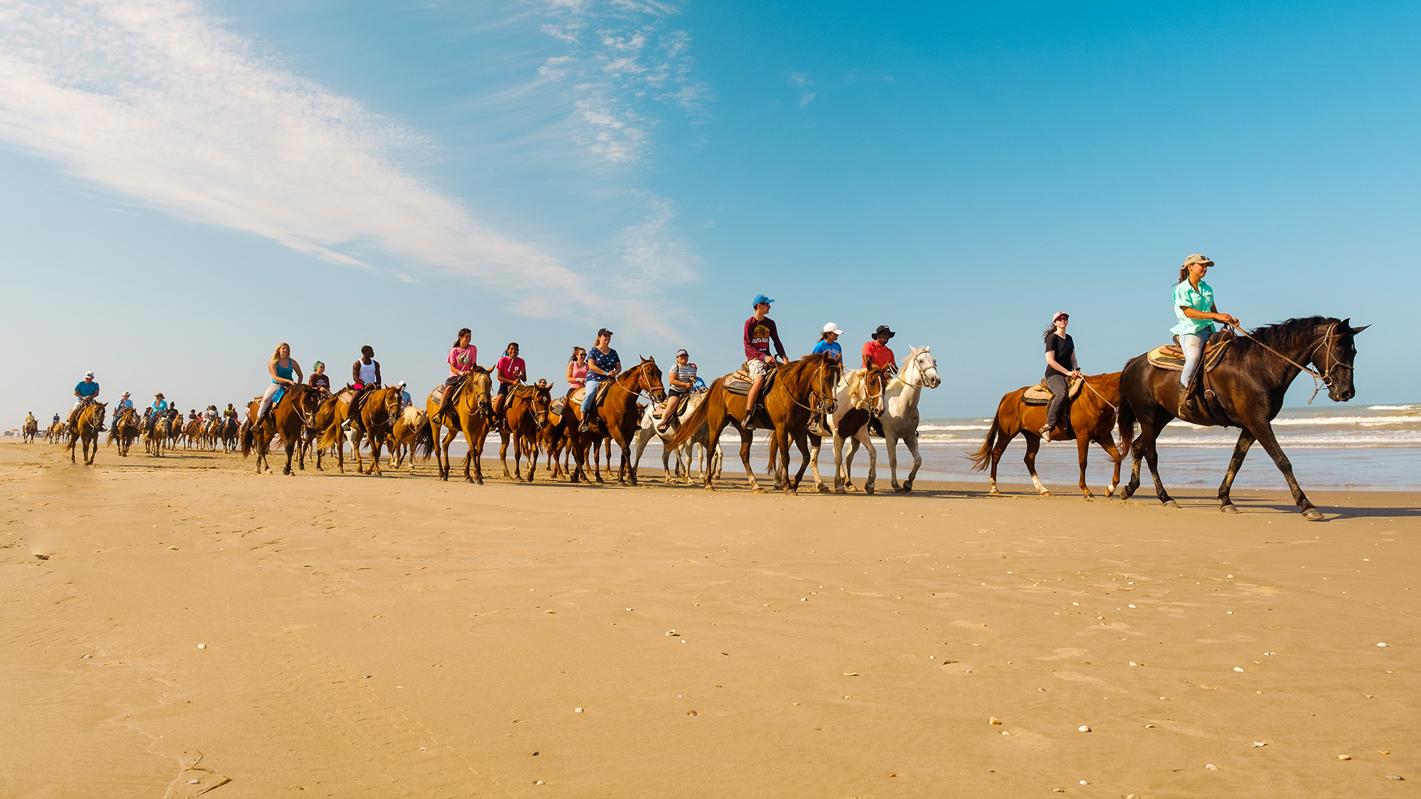 Group riding on horseback on the beach.