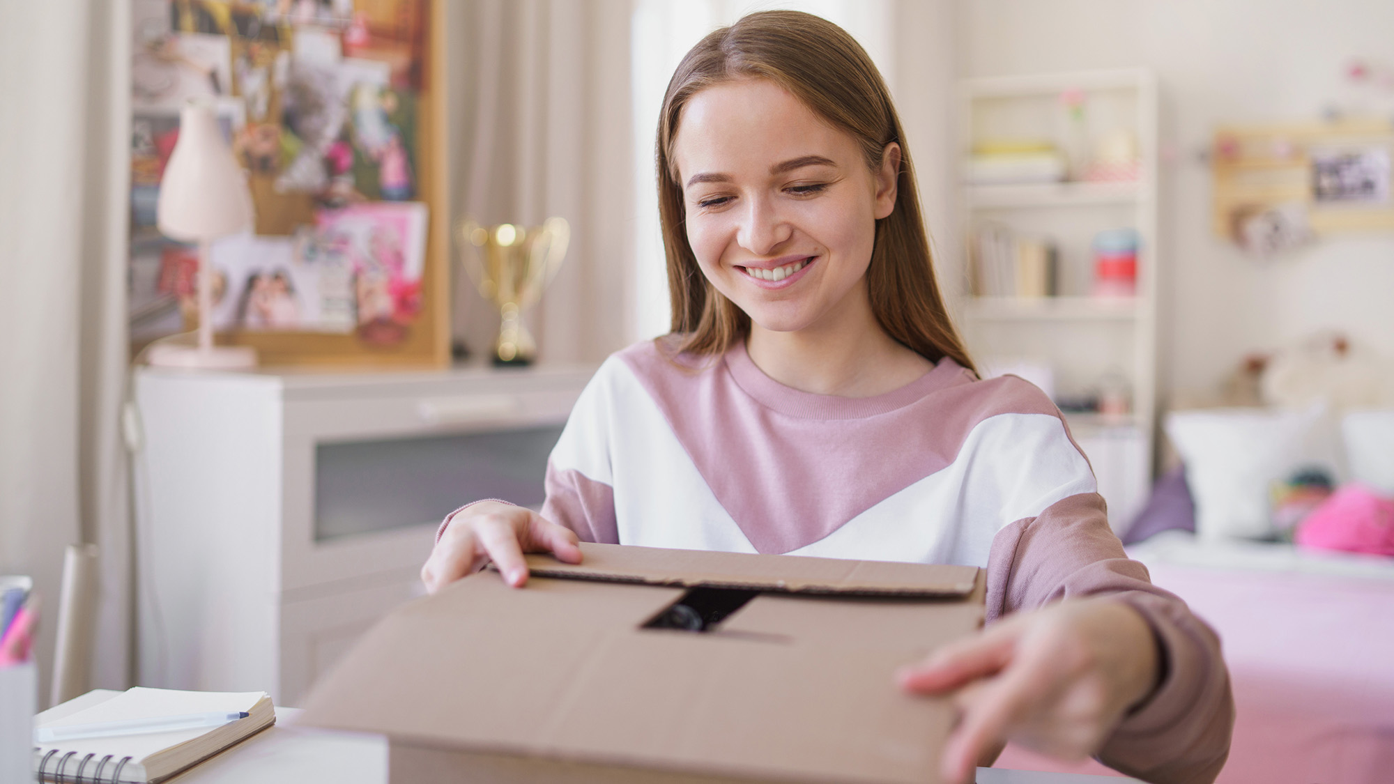 Girl opening a package in her room.