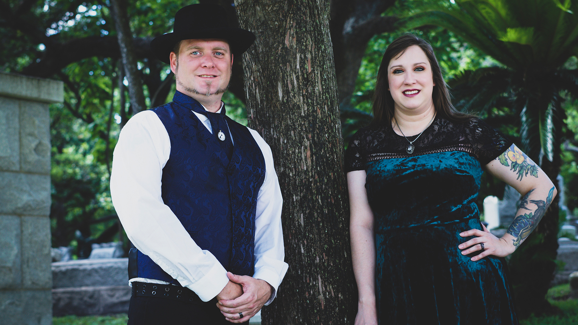 Man and woman posing outside in old-timey clothes.