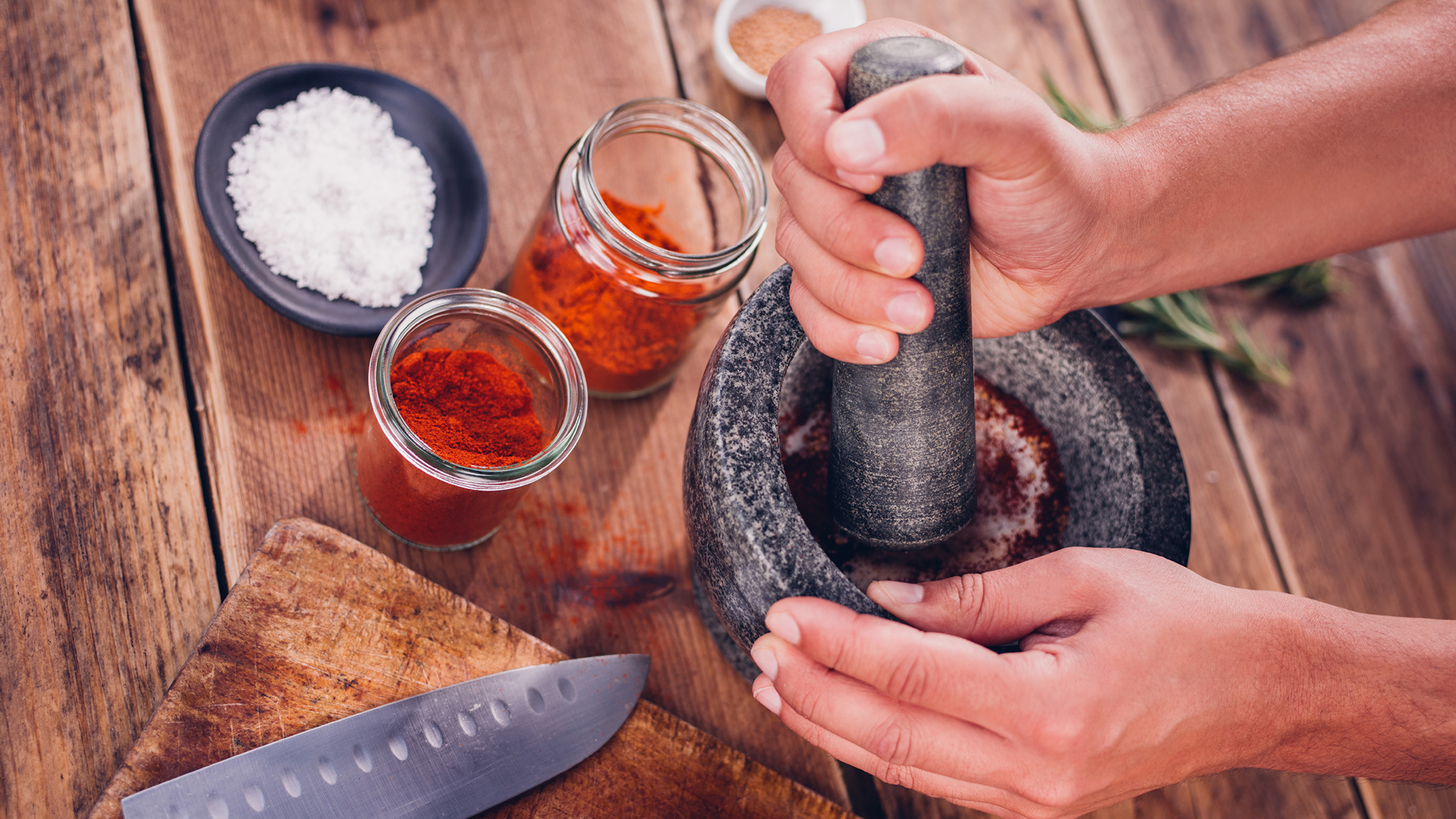 Person using a mortar and pestle to make barbecue red rub seasoning.