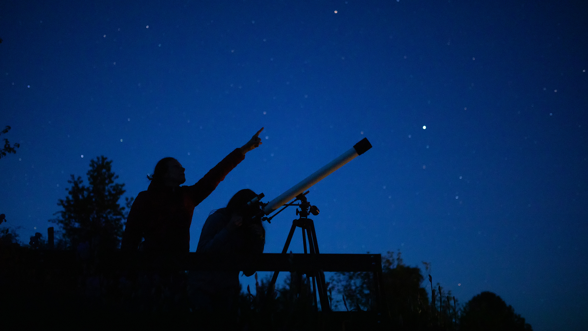 People looking through telescopes in the night.