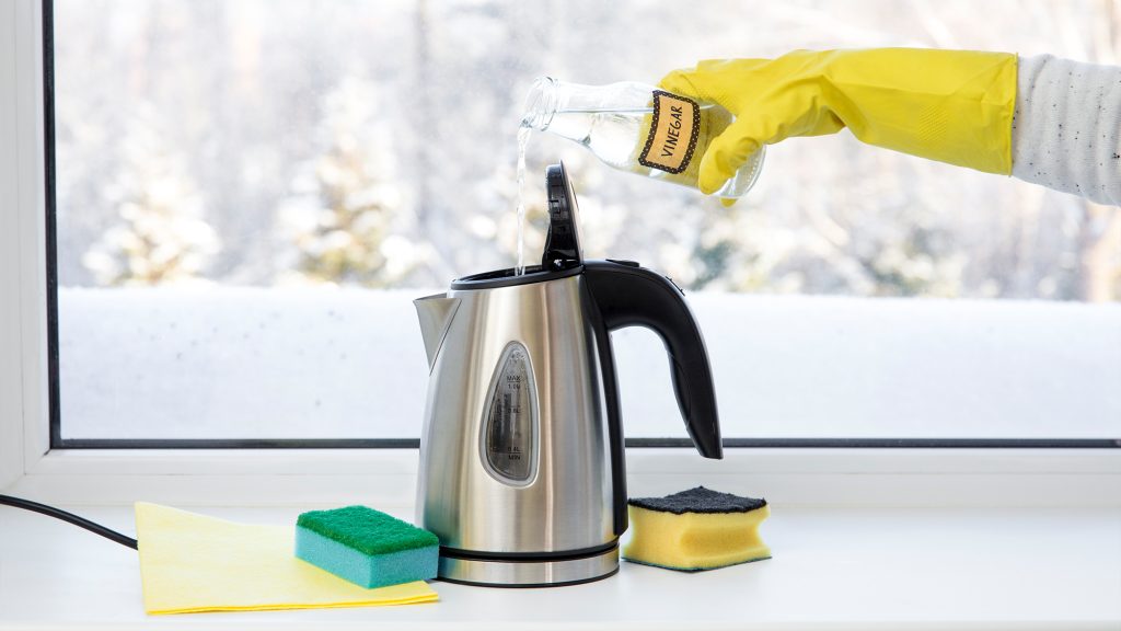 Person using vinegar to clean coffeepot.