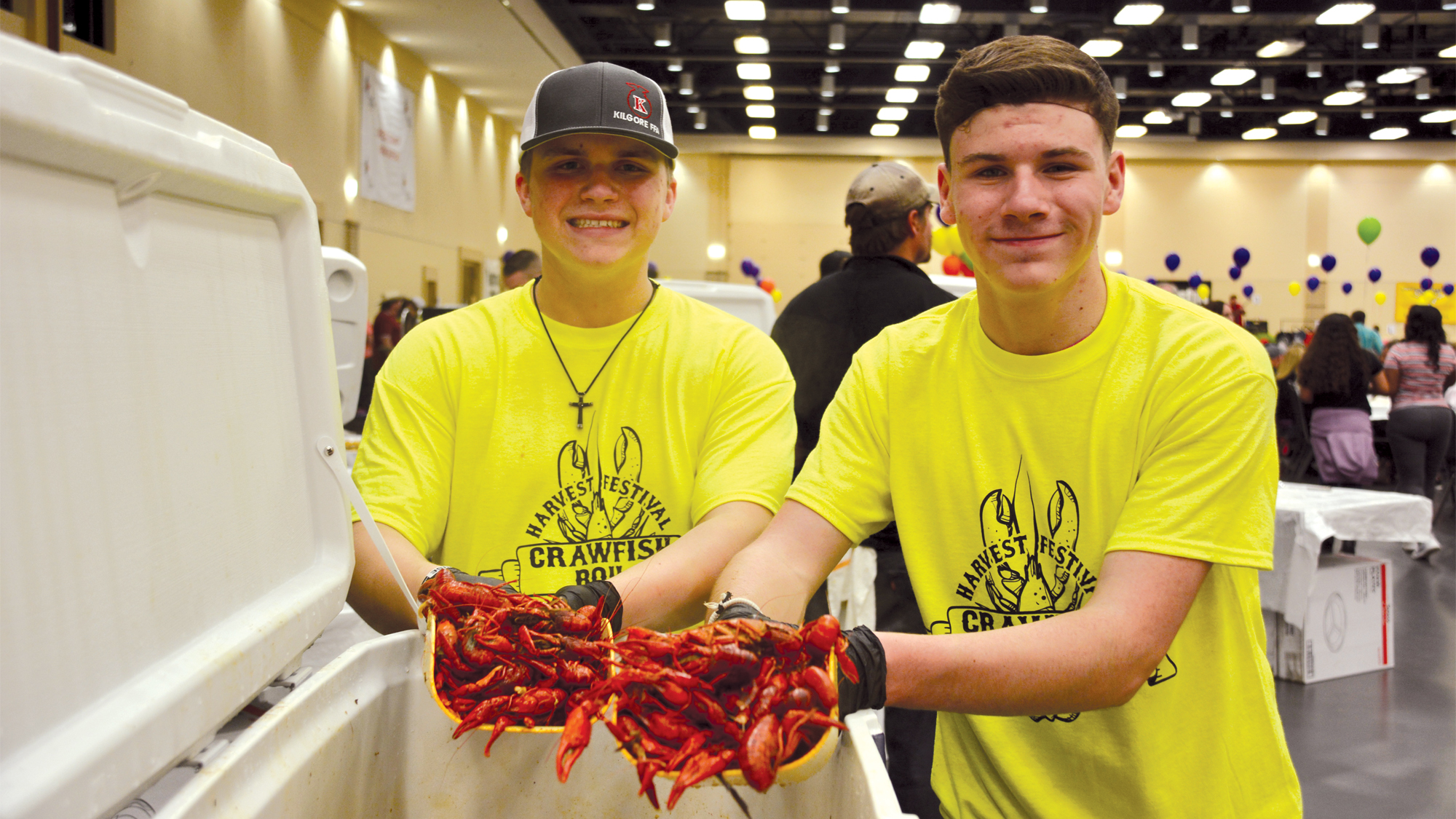 Two guys holding cooked crawfish.
