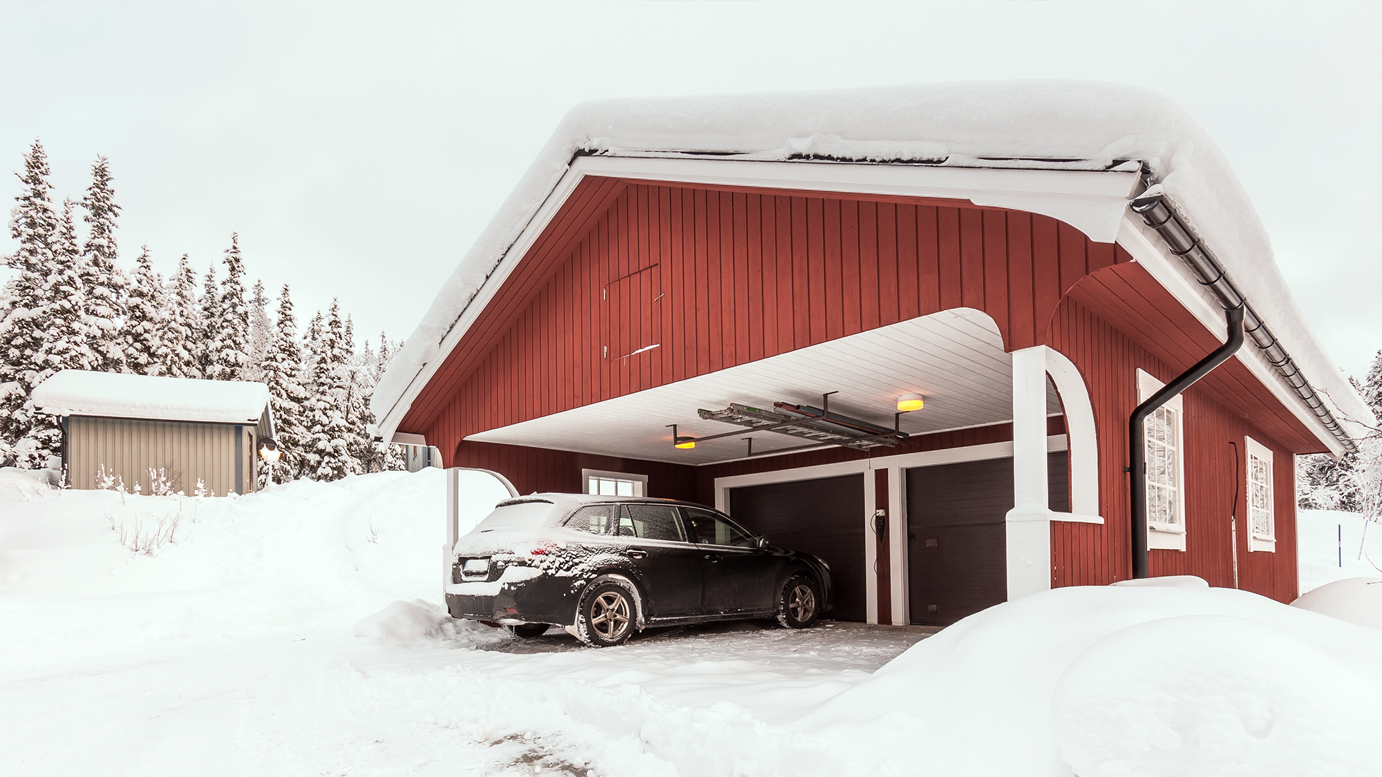 Car parked under a carport in the snow.