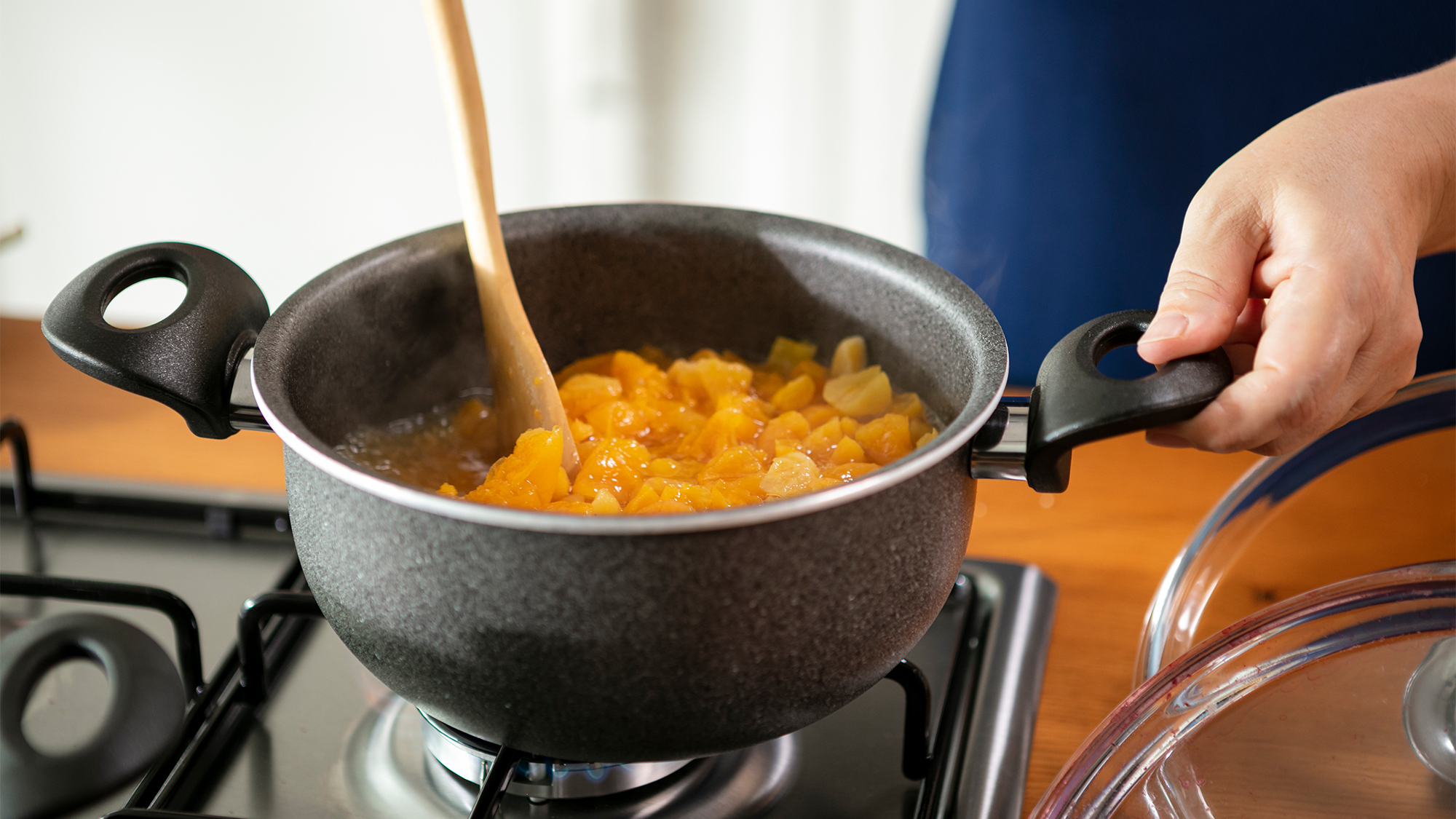 Person making jam from fruit on stove.