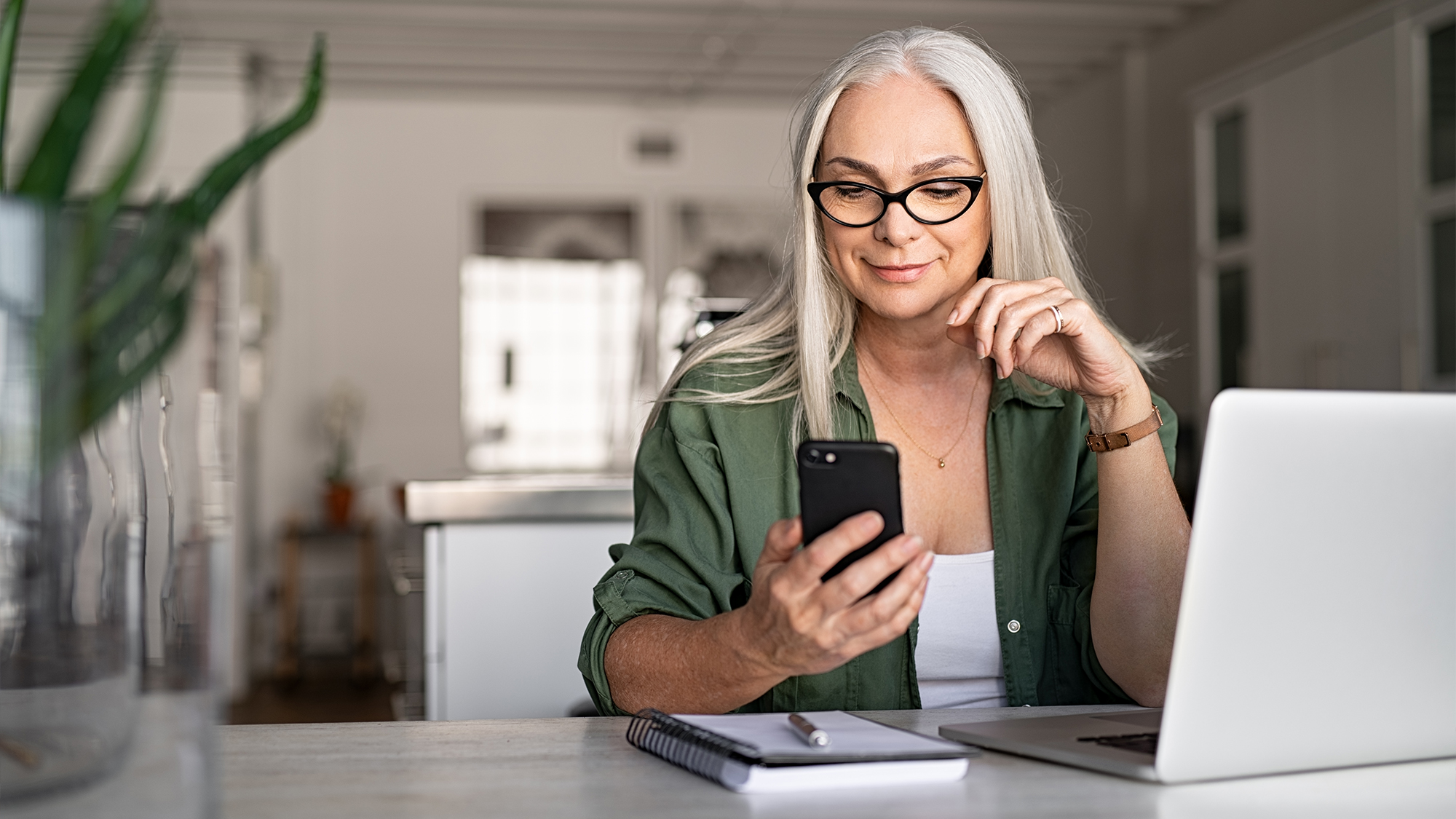 Woman at desk reading something on her phone.