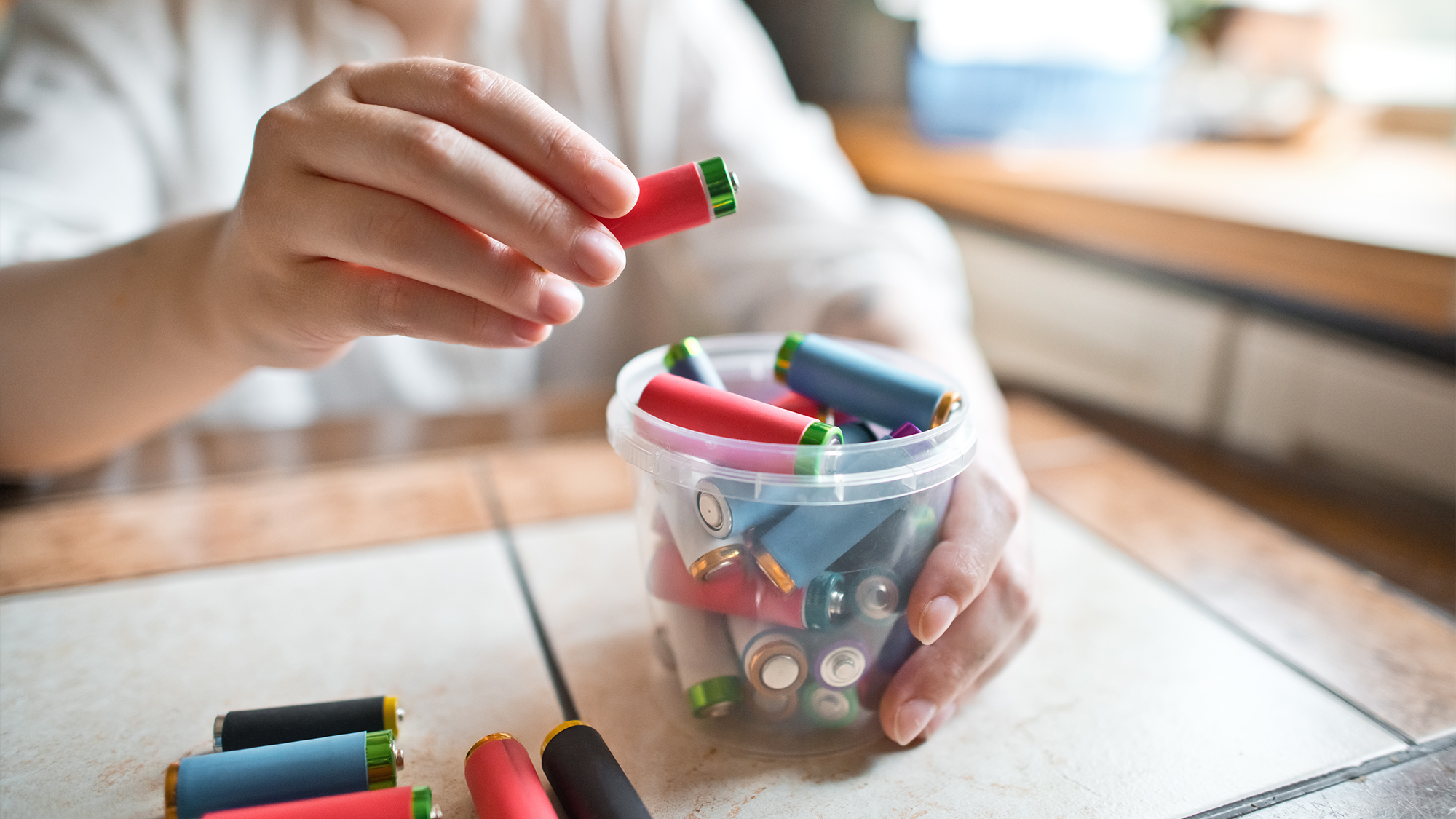 Person putting batteries in a container.