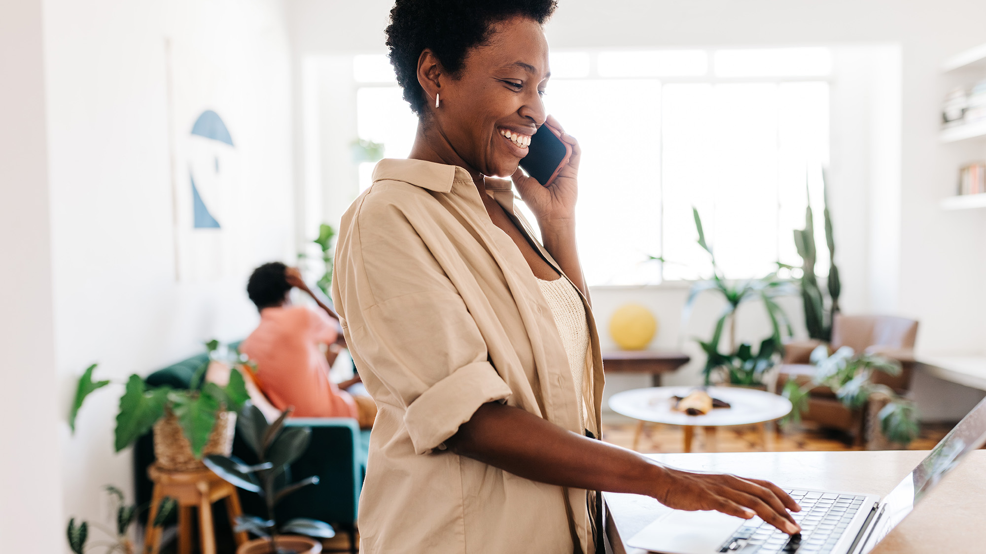 Woman talking on the phone and at the computer in a room.