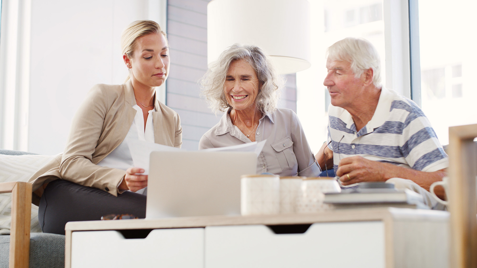 One younger woman and an older couple reviewing documents together.