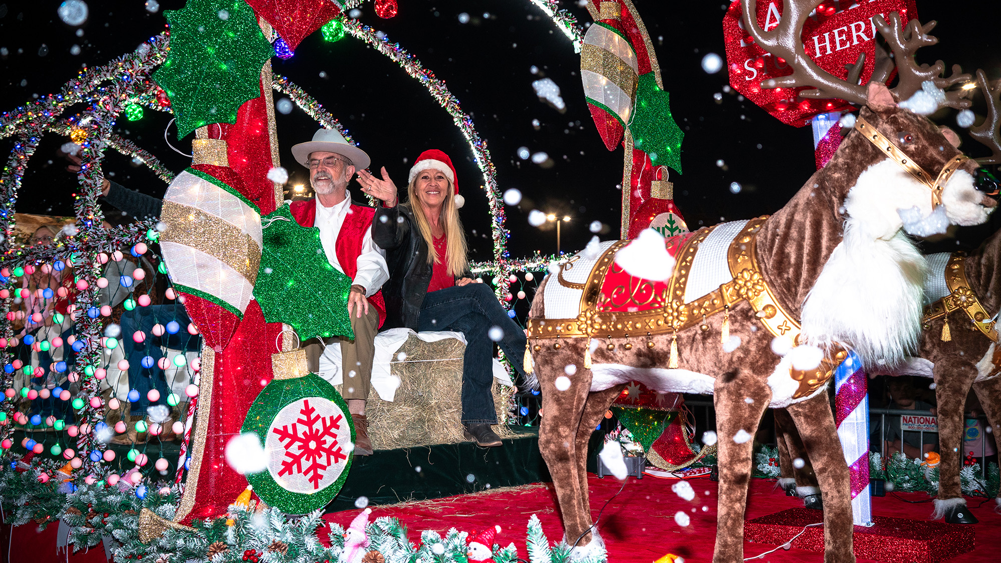 Man and woman on a holiday parade float.