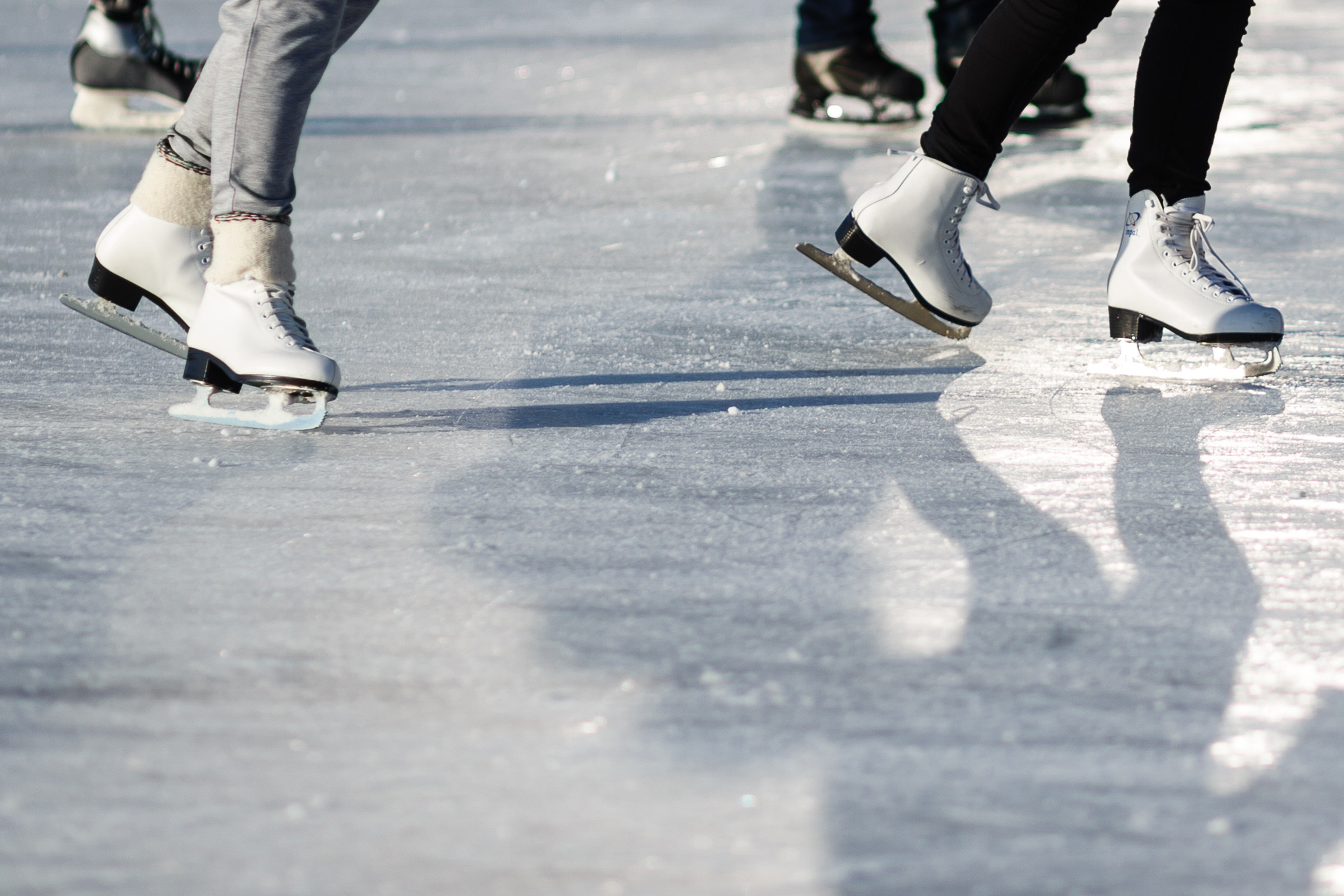 Close up of people ice skating on a rink.