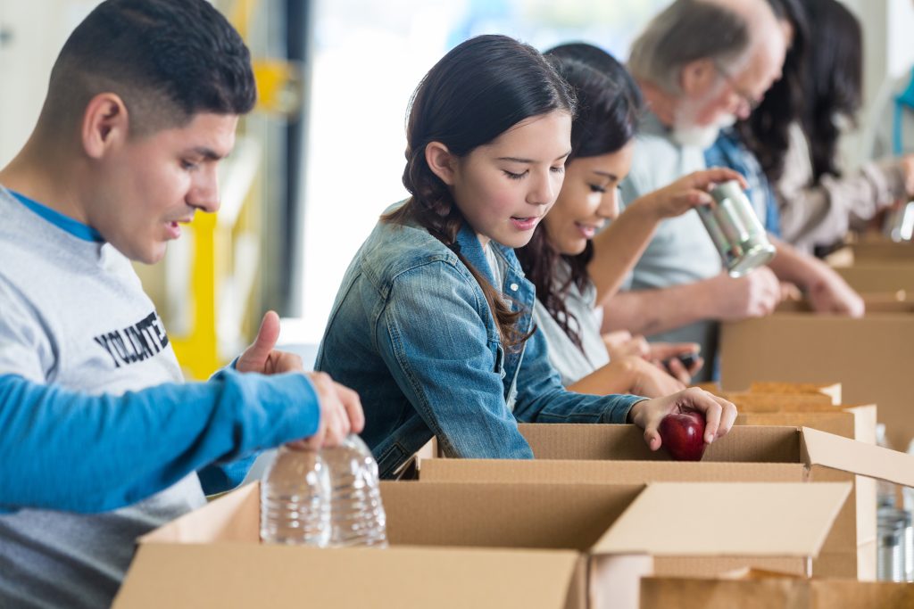 People volunteering to pack food in boxes.