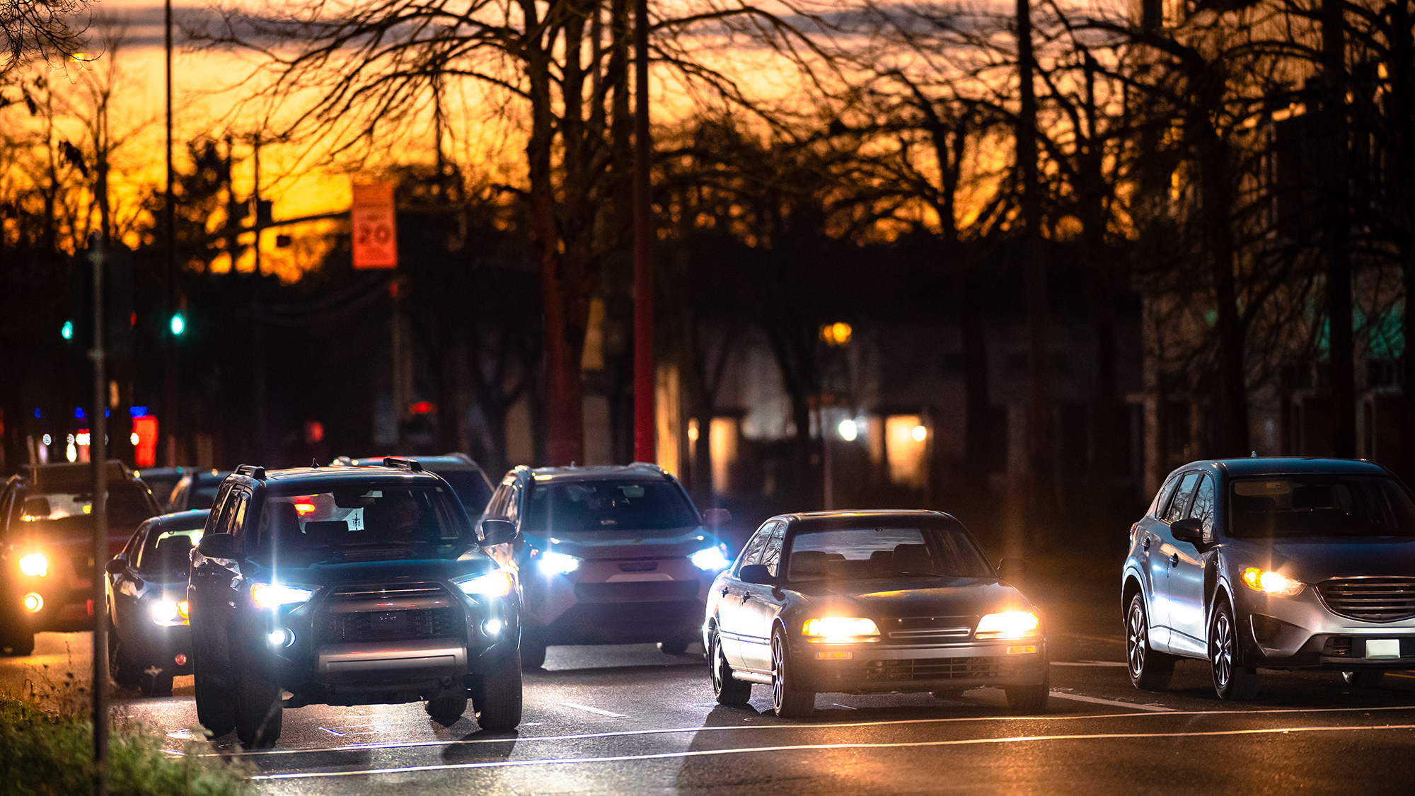 Cars on a street with headlights on.