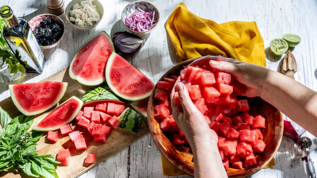 Person making watermelon salad.