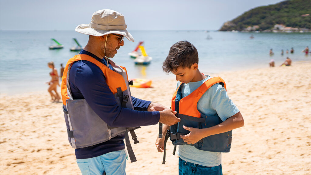 People wearing life jackets on a beach.